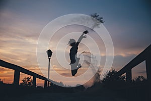 Silhouette of a happy woman jumping in sand at sunset