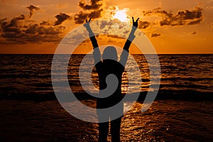 Silhouette of Happy woman showing two fingers while sunset at sea,Overcoming obstacle concept