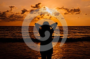 Silhouette of Happy woman standing with hands on head while sunset at sea,Freedom concept