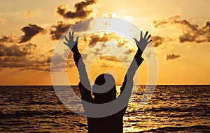 Silhouette of Happy woman standing with hands raise up while sunset at sea,Light flare,Enjoys of resting time,Freedom concept