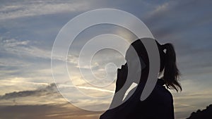 Silhouette of happy woman talking on the mobile phone during beautiful sunrise