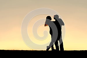 Silhouette of Happy Young Couple Dancing at Sunset