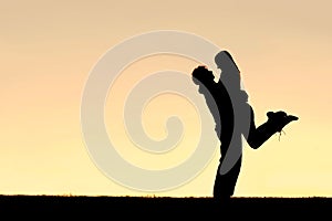 Silhouette of Happy Young Couple Hugging Outside at Sunset