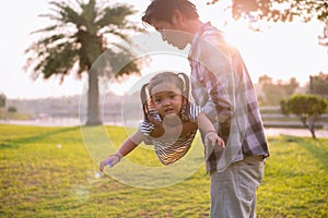 A silhouette of a happy young father harmonious family outdoors laughing and playing in the summer on the sunset background.