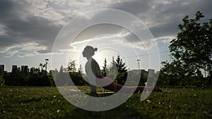 Silhouette of healthy adult female yoga practitioner preforming Downward Facing Dog Pose Adho Mukha Svansana at sunset