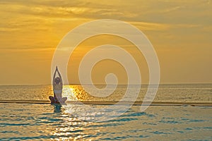 Silhouette healthy lifestyle woman practicing yoga and exercising relax vital meditate on swimming pool and the beach at sunset.