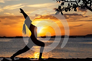 Silhouette healthy woman lifestyle exercising vital meditate and practicing yoga on the rock in beach