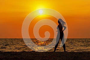 Silhouette healthy woman lifestyle exercising vital meditate and practicing yoga on the rock in beach at sunset.