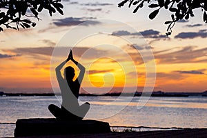 Silhouette healthy woman yoga balance body exercising vital meditate and practicing on the rock outdoor in the beach at sunset.