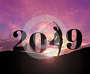 Silhouette of healthy woman practicing yoga on the hill and 2019 years with sky twilight with filter lens flare. concept