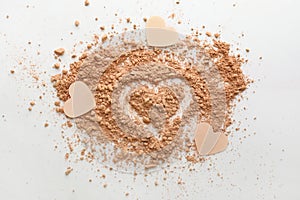 Silhouette of heart with crumbled face powder on white background