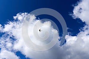 Silhouette of a helicopter against a blue sky with clouds