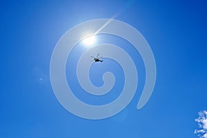 Silhouette of a helicopter against a blue sky with clouds