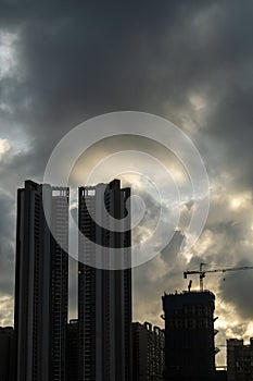 Silhouette of a high rise skyscraper under construction with dark dramatic monsoon sky in the suburb