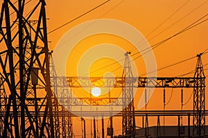 Silhouette high voltage electric pillars pylon in electric power plants substation on sunset