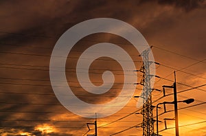 Silhouette high voltage electric pylon and electrical wire with an orange sky. Electricity poles at sunset. Power and energy