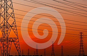 Silhouette high voltage electric pylon and electrical wire with an orange sky. Electricity poles at sunset. Power and energy