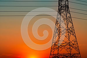 Silhouette high voltage electric pylon and electrical wire with an orange sky. Electricity poles at sunset. Power and energy