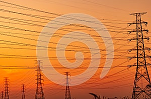 Silhouette high voltage electric pylon and electrical wire with an orange sky. Electricity poles at sunset. Power and energy