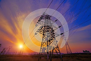 Silhouette high voltage electric pylon and electrical wire with an orange sky. Electricity poles at sunset. Power and energy