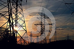 Silhouette high voltage electric tower on summer sunset background.