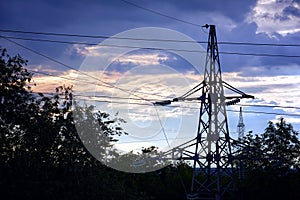 Silhouette of a high-voltage power line tower against cloudy sky in the evening