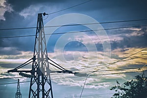 Silhouette of a high-voltage power line tower against cloudy sky in the evening