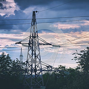 Silhouette of a high-voltage power line tower against cloudy sky in the evening