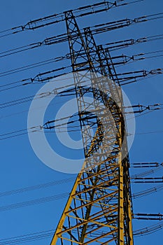 Silhouette of a high-voltage pylon in the blue evening sky.