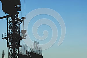 Silhouette of Highrise Crane Lifting Concrete Pourer at a Construction Site