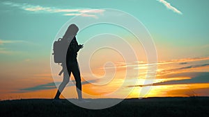 Silhouette hiker girl traveler with smartphone navigation search ways. the girl nature search position navigation slow