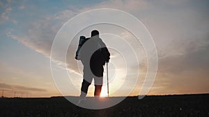 Silhouette hiker man tracking with backpack and trekking pole at sunset on the background. Alone with nature. Healthy