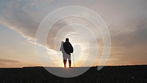 Silhouette hiker man tracking with backpack and trekking pole at sunset on the background. Alone with nature. Healthy