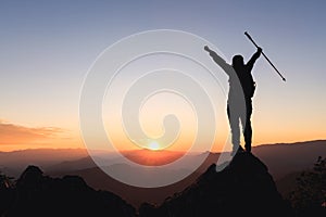 Silhouette of hiker standing on top of hill and enjoying sunrise over the valley.  The man thank God on the mountain and success