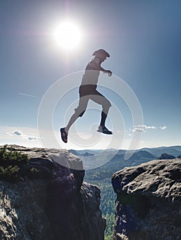 Silhouette of hiking man jumping over the mountains at sunset