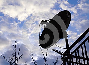 Silhouette of home satellite dish antenna on the balcony with cl