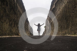 Silhouette on the horizon of young happy and active woman running and jumping excited on road between mountain cliffs feeling free