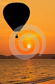 Silhouette hot air balloons floating over tropical beach on sunset