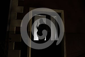 The silhouette of a human in front of a window at night. Scary scene halloween concept of blurred silhouette of maniac