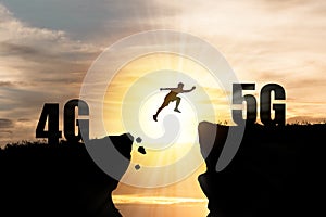 Silhouette Human jumping from 4G cliff to 5G cliff with cloud sky and sunset. Technology change and transformation concept