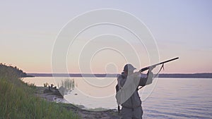 Silhouette of the hunter on a duck hunt near a beautiful lake. Shooting hunter.