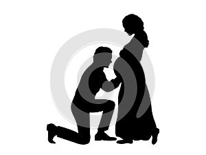 Silhouette husband kneels in front of his pregnant wife side view