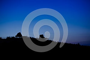 Silhouette of huts on a hill against twilight