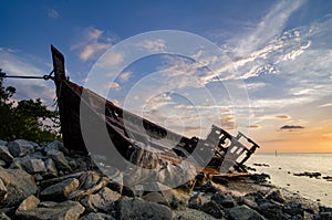 Silhouette image of abandon shipwrecked on rocky shoreline. dark cloud and soft on water