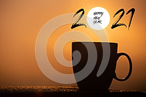 Silhouette image coffee cup with text happy new year 2021 on a sunrise background