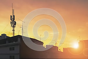 Silhouette image of communication antenna telephone network in the city with sunset sky background
