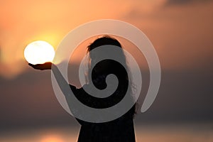 Silhouette image of girl holding sun