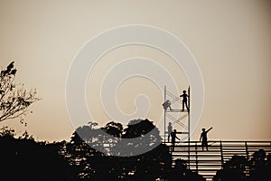 Silhouette image of a group of workers working on scaffolding for construction