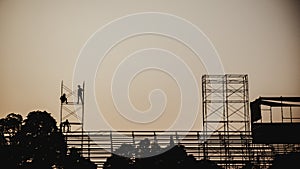 Silhouette image of a group of workers working on scaffolding for construction