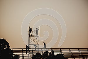 Silhouette image of a group of workers working on scaffolding for construction